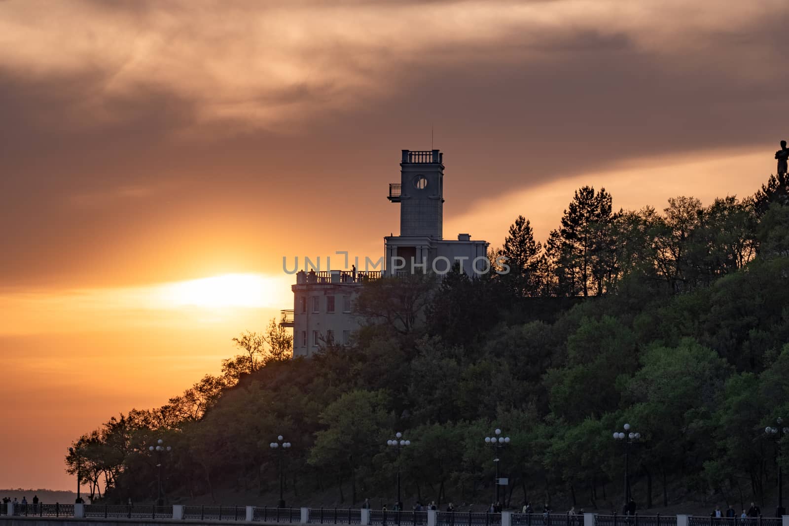 Sunset on the embankment of the Amur river in Khabarovsk. The sun set over the horizon. The embankment is lit by lanterns.