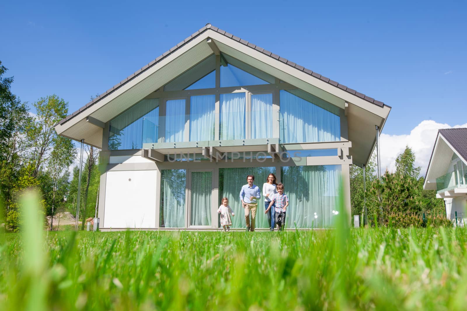 Happy family of parents and two children playing running in front of their house