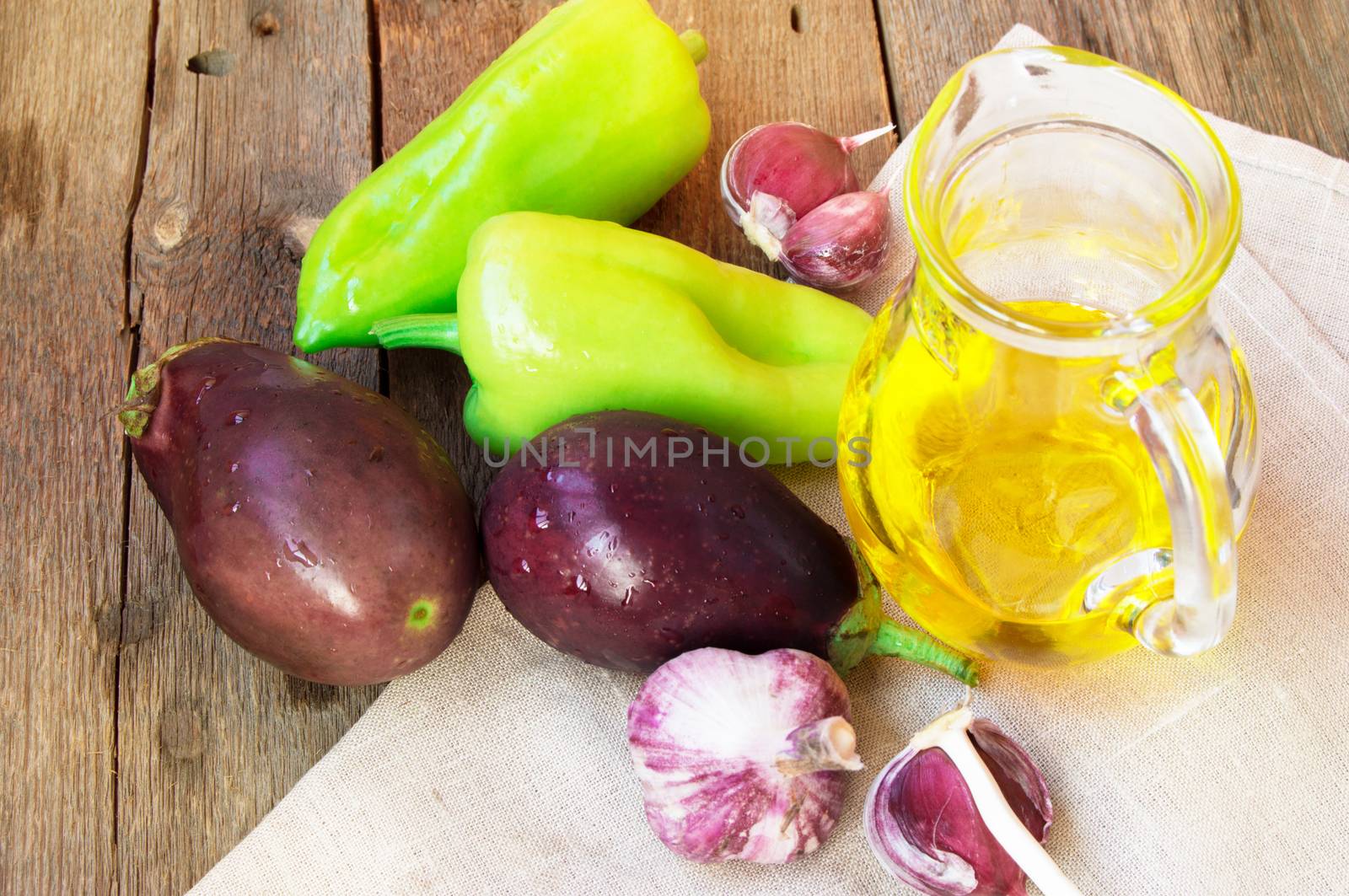 Raw eggplant, garlic, olive oil, sweet pepper, healthy eating and diet concept on the old wooden background.