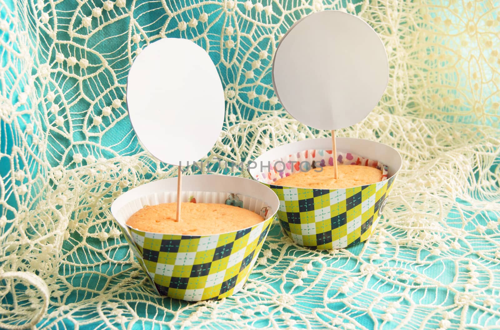 Two cupcake on blue napkin with lace embroidery card space instance, the layout of the cards and invitations for a holiday.