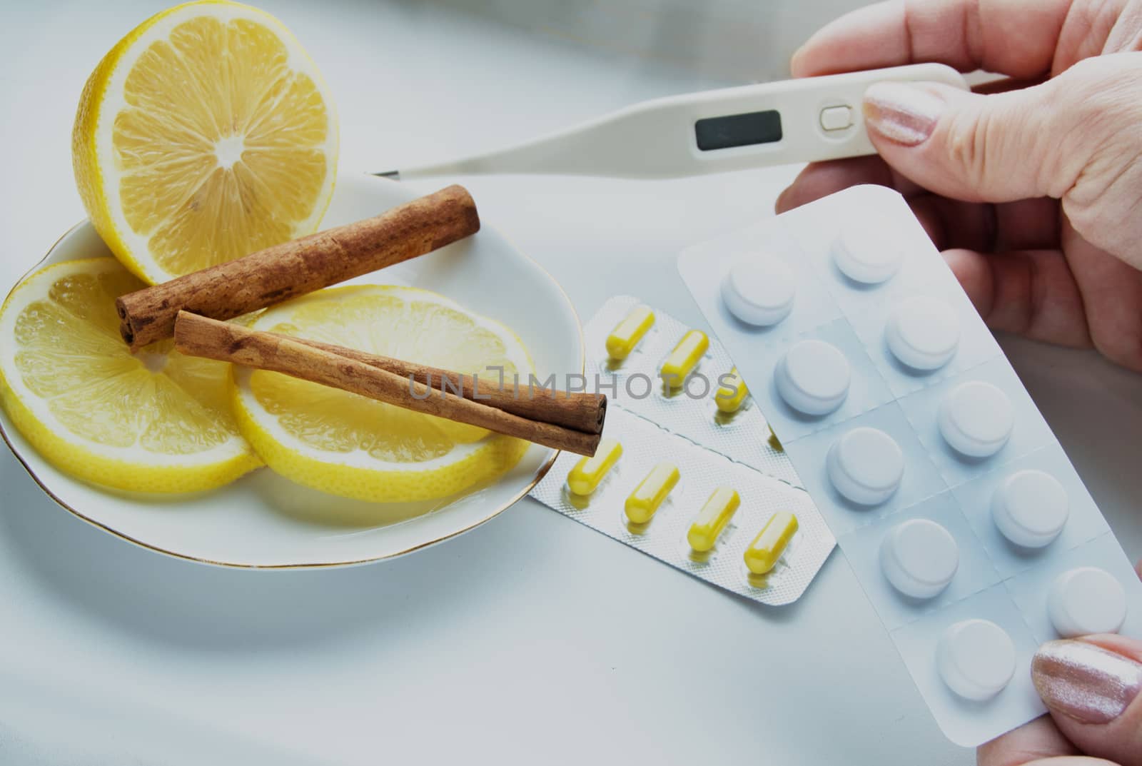 Thermometer in hands, tablets, lemon with cinnamon, the concept of treatment of colds.