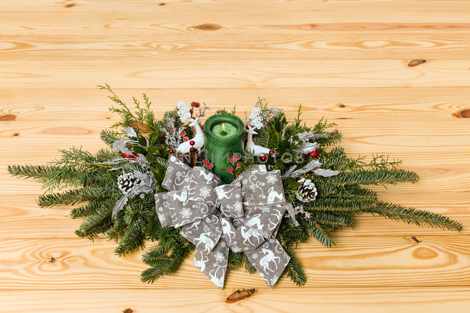 Christmas festive decoration with red baubles, holly with red berries , snow covered pine cones and winter greenery over woodpanel background.