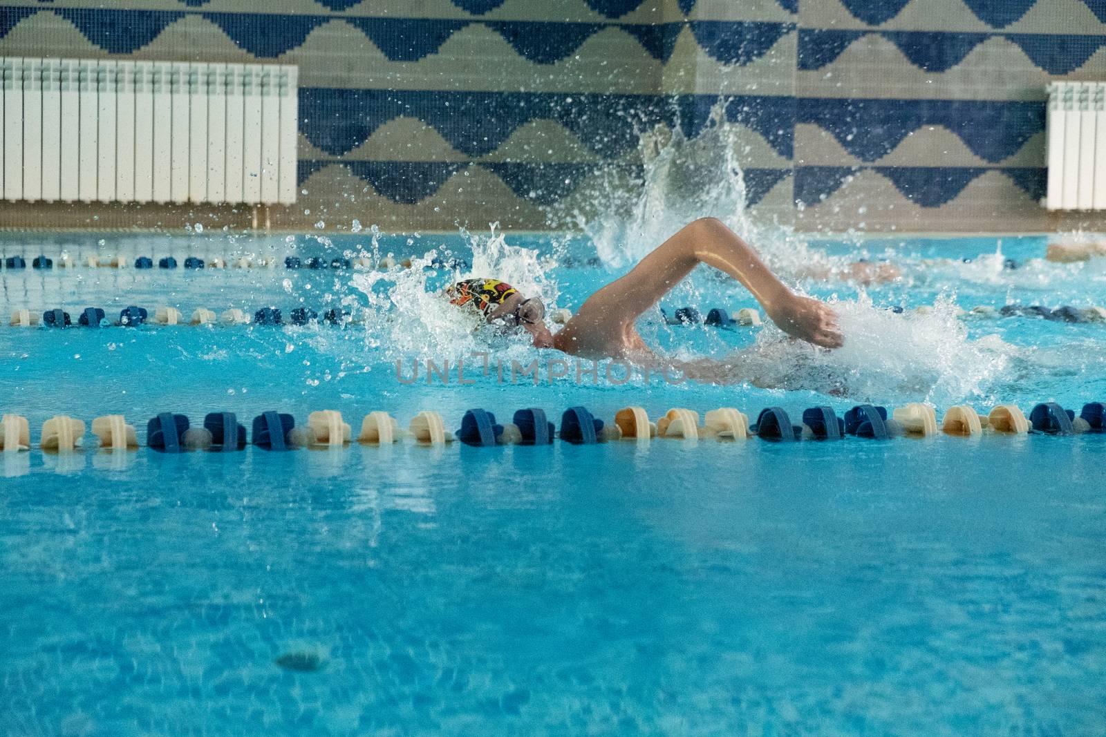 Children swimming freestyle. Indoor swimming pool with clear blue water.