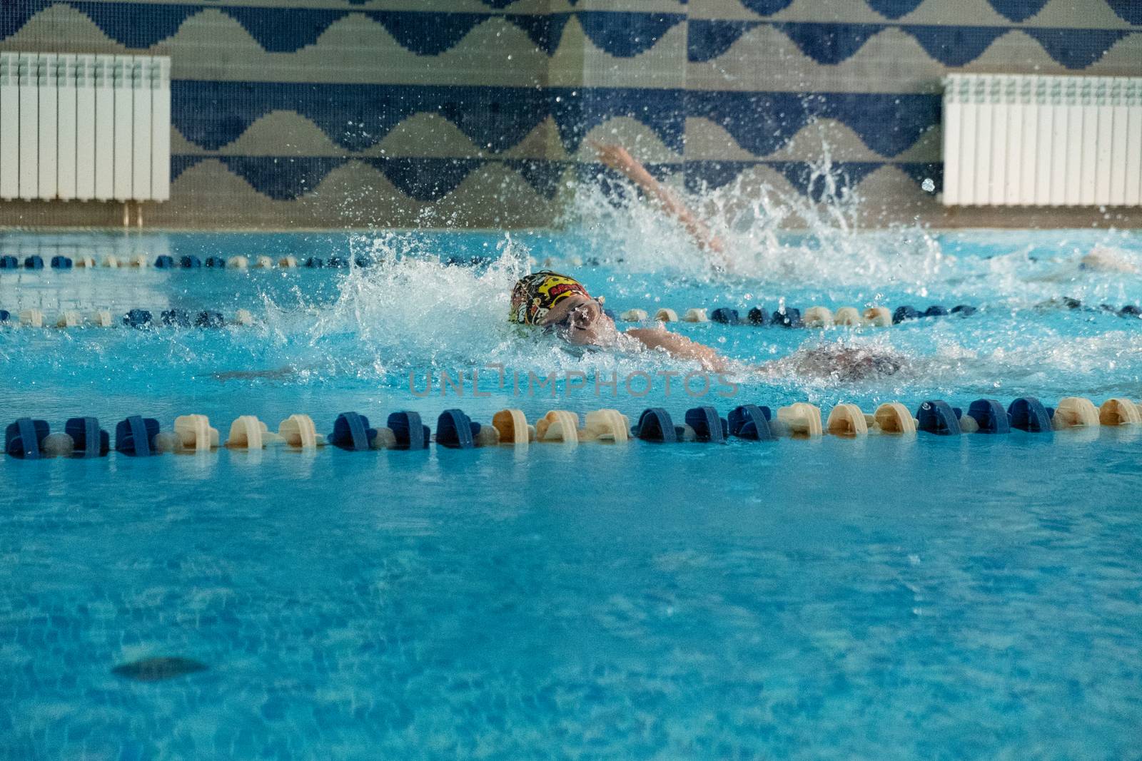 Children swimming freestyle. Indoor swimming pool with clear blue water. by rdv27