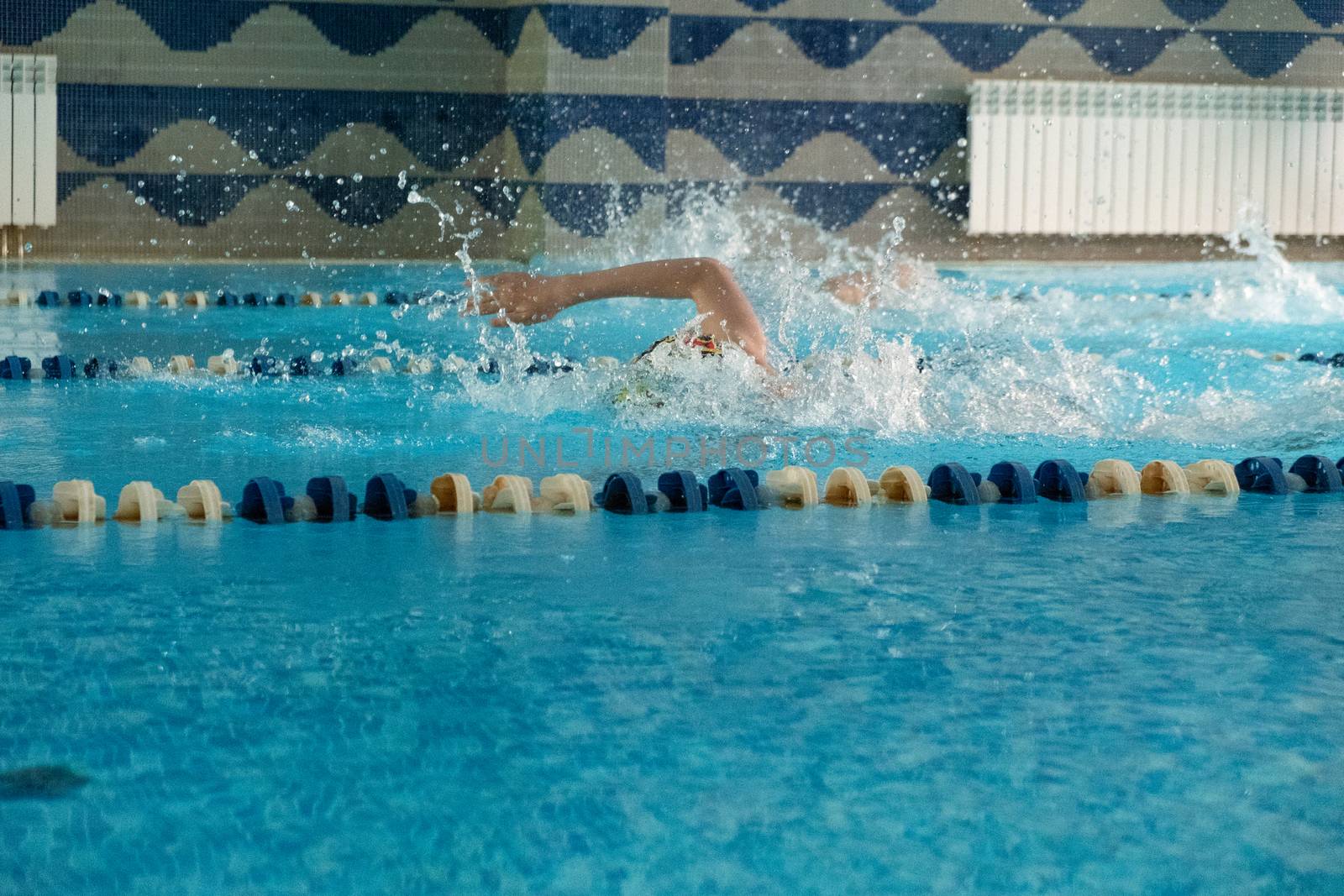 Children swimming freestyle. Indoor swimming pool with clear blue water. by rdv27