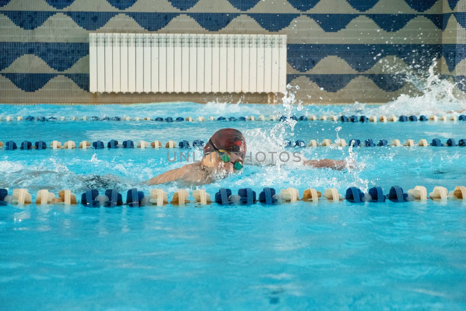 Children swimming freestyle. Indoor swimming pool with clear blue water.