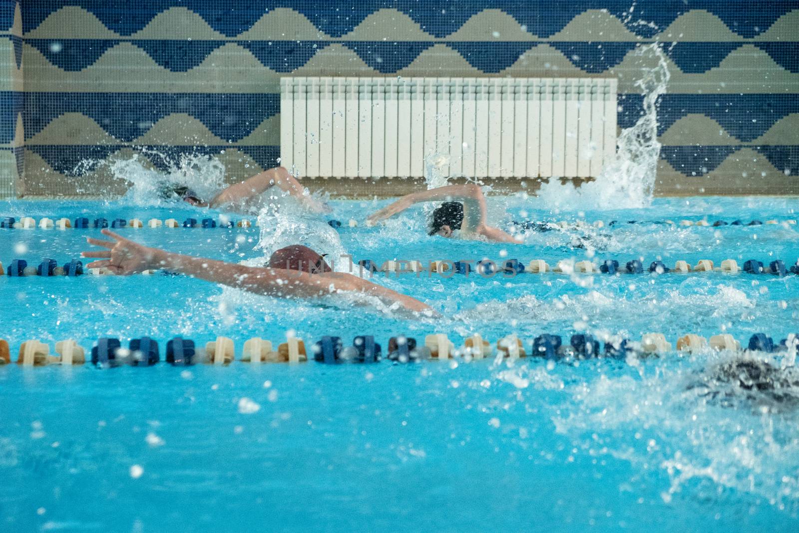 Children swimming freestyle. Indoor swimming pool with clear blue water.