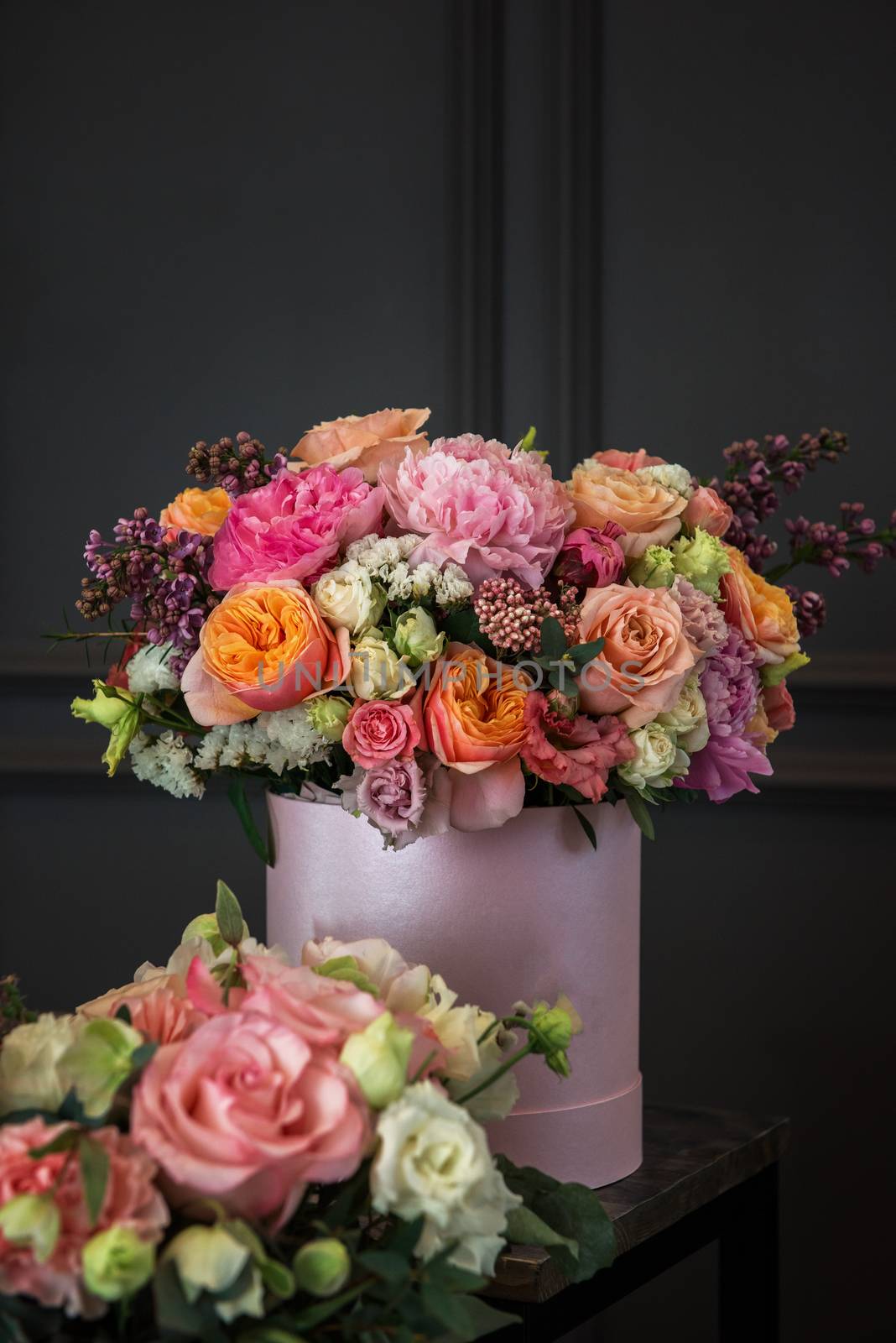 Bouquet of different beauty flowers in round present box on dark background