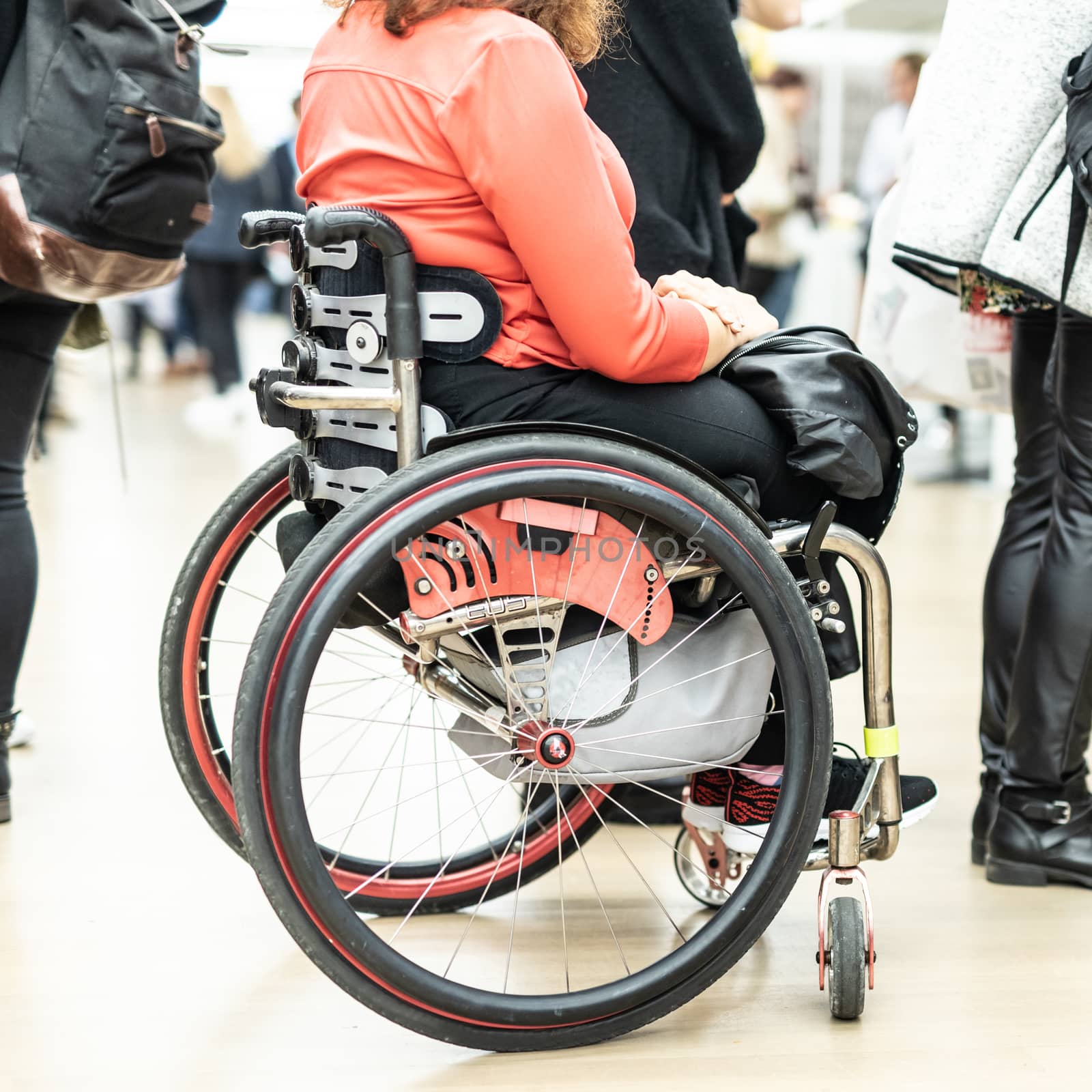 Close up of unrecognizable hanicapped woman on a wheelchair queuing in line to perform everyday tasks. by kasto