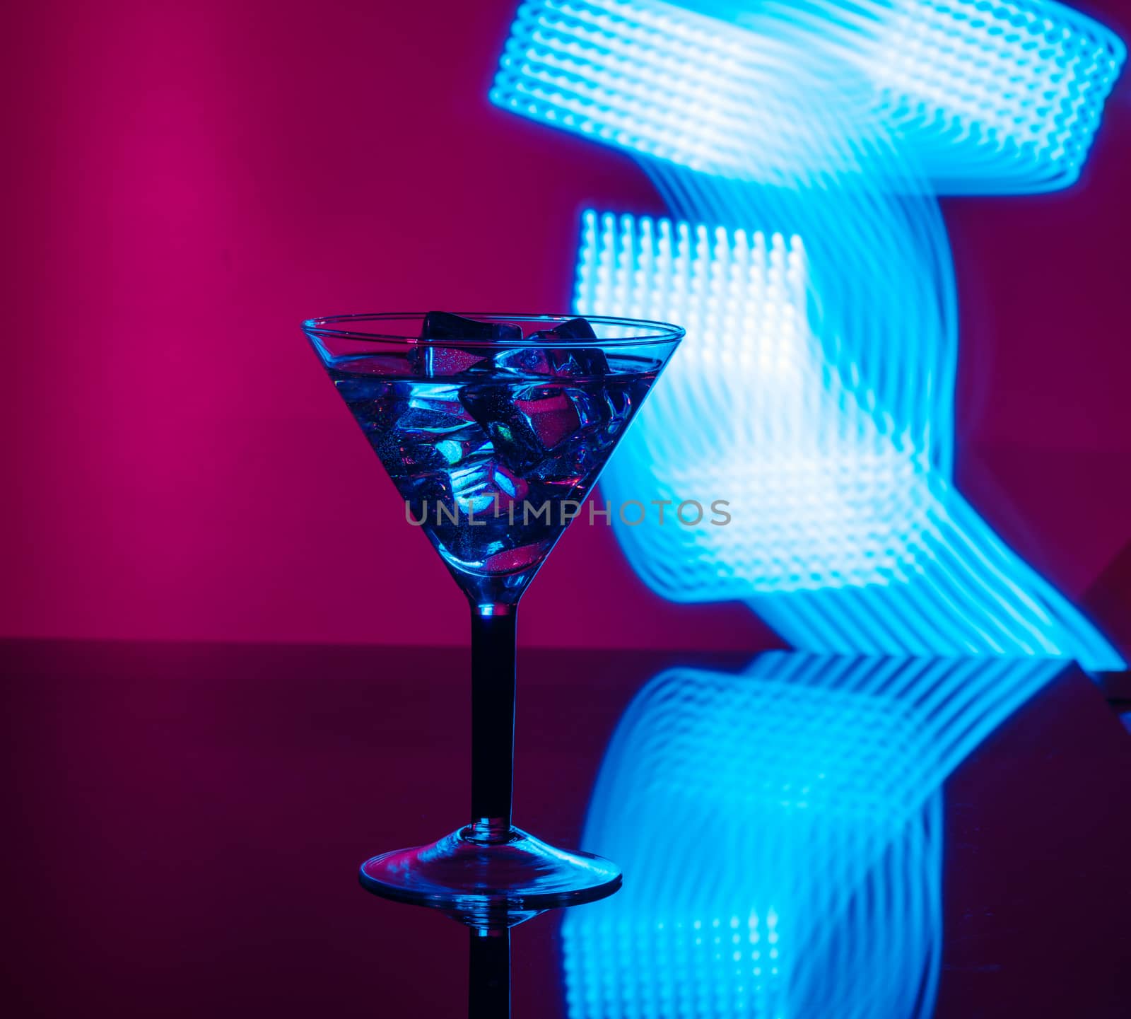 A glass of martini with ice cubes on a club background