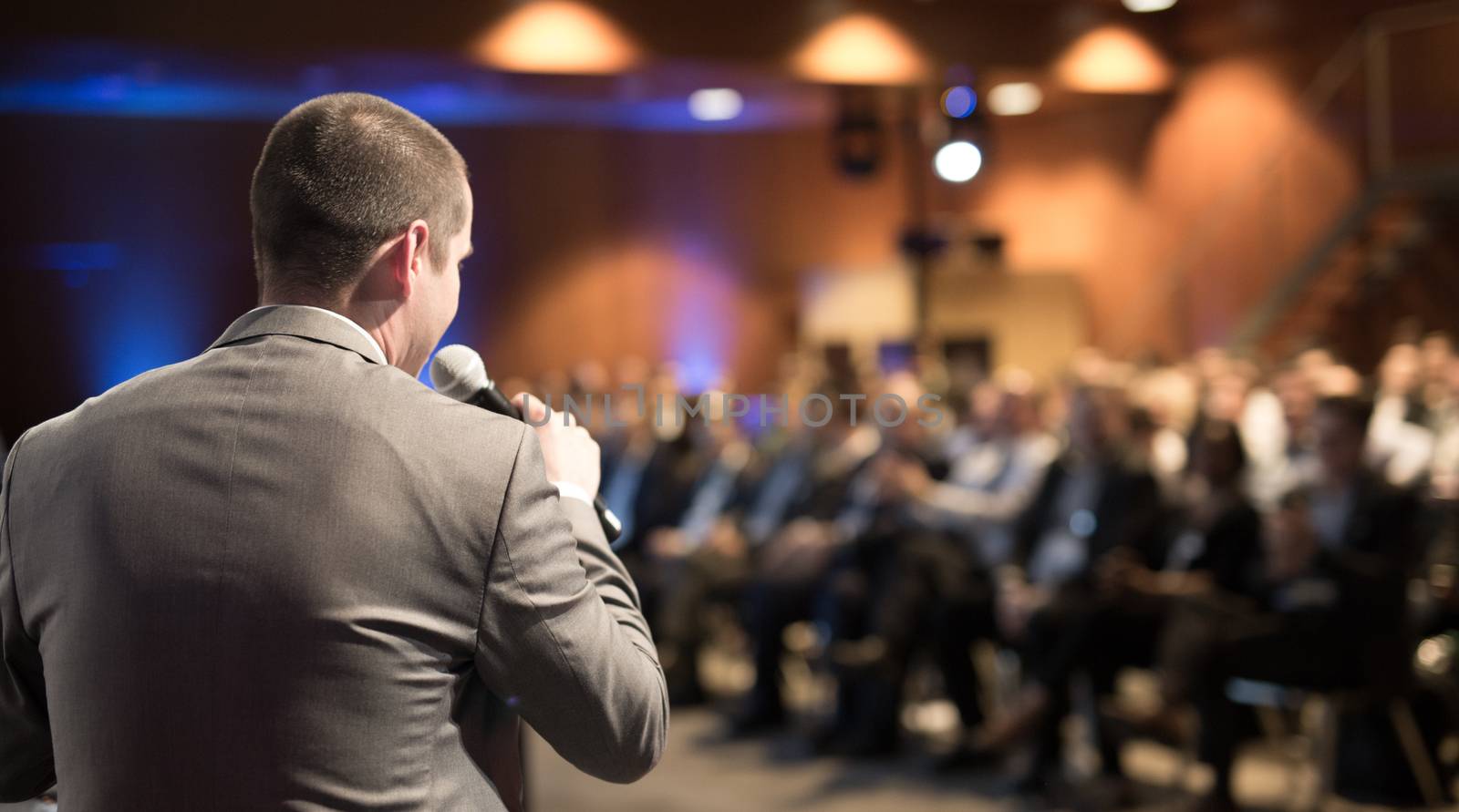 Speaker giving a talk on corporate business conference. Unrecognizable people in audience at conference hall. Business and Entrepreneurship event.