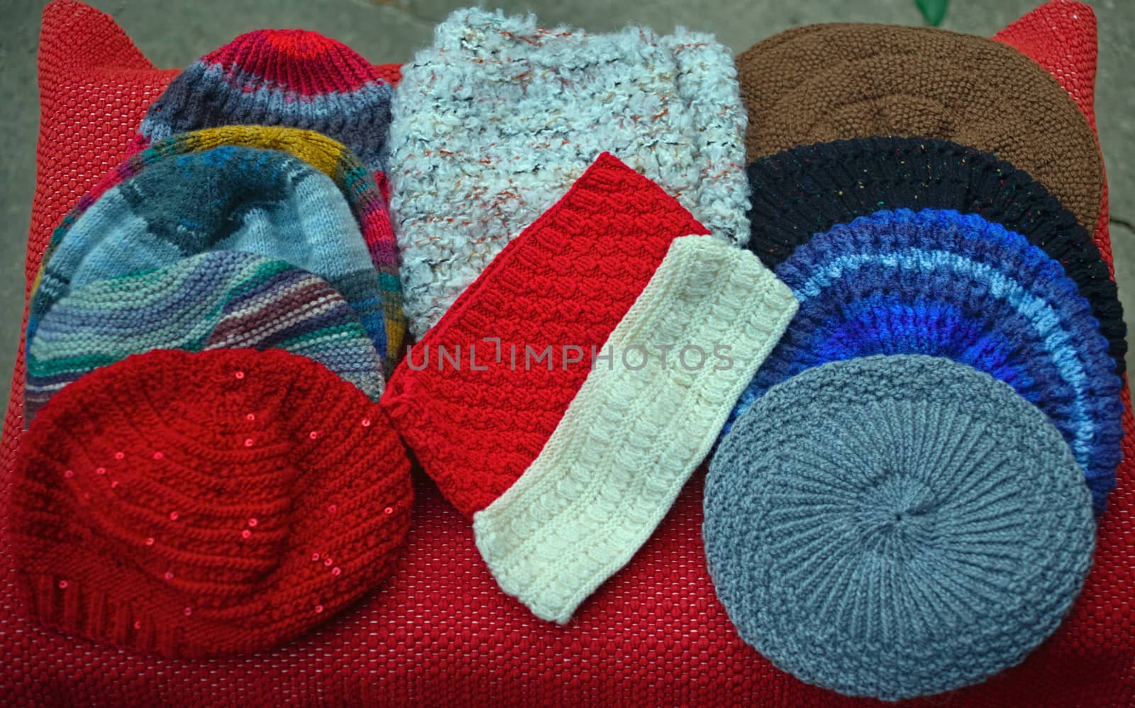 Many colorful handmade traditional winter hats on table