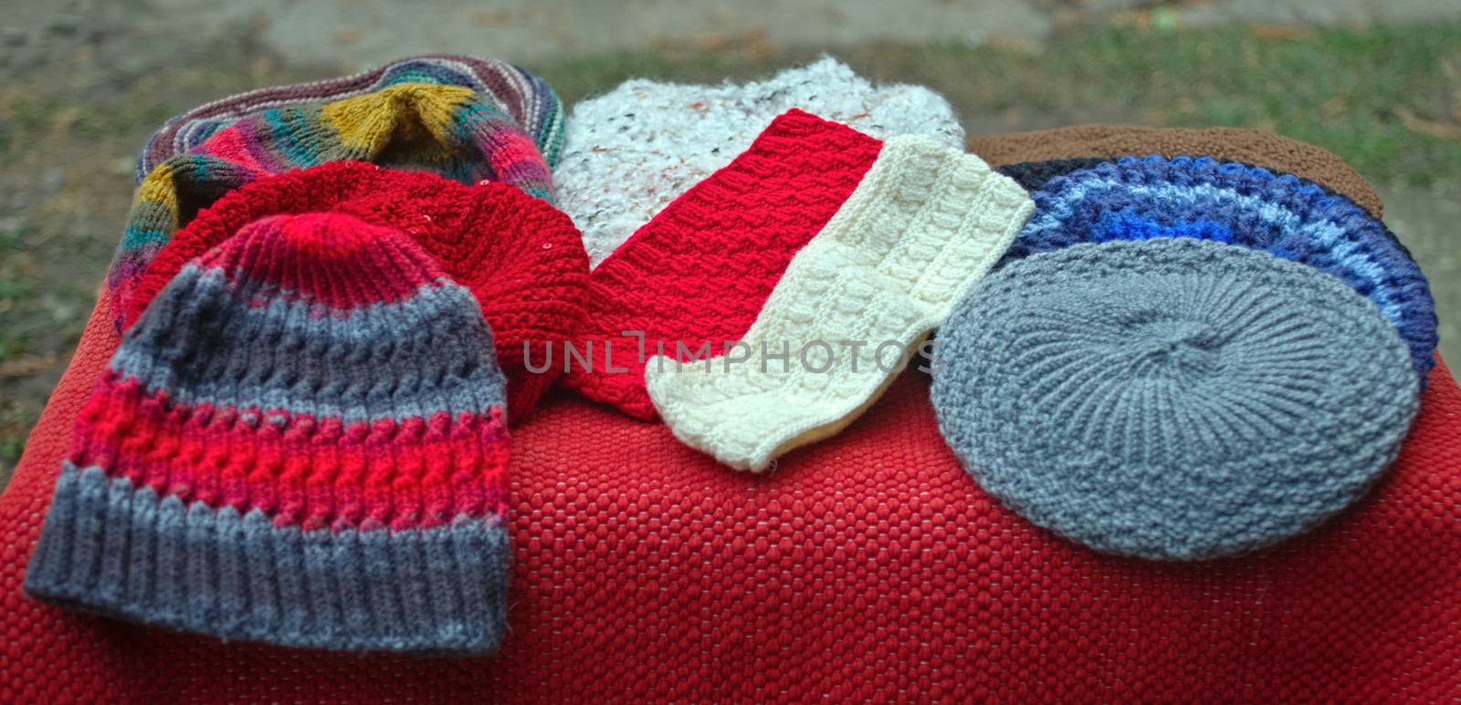 Many colorful handmade traditional winter hats on table