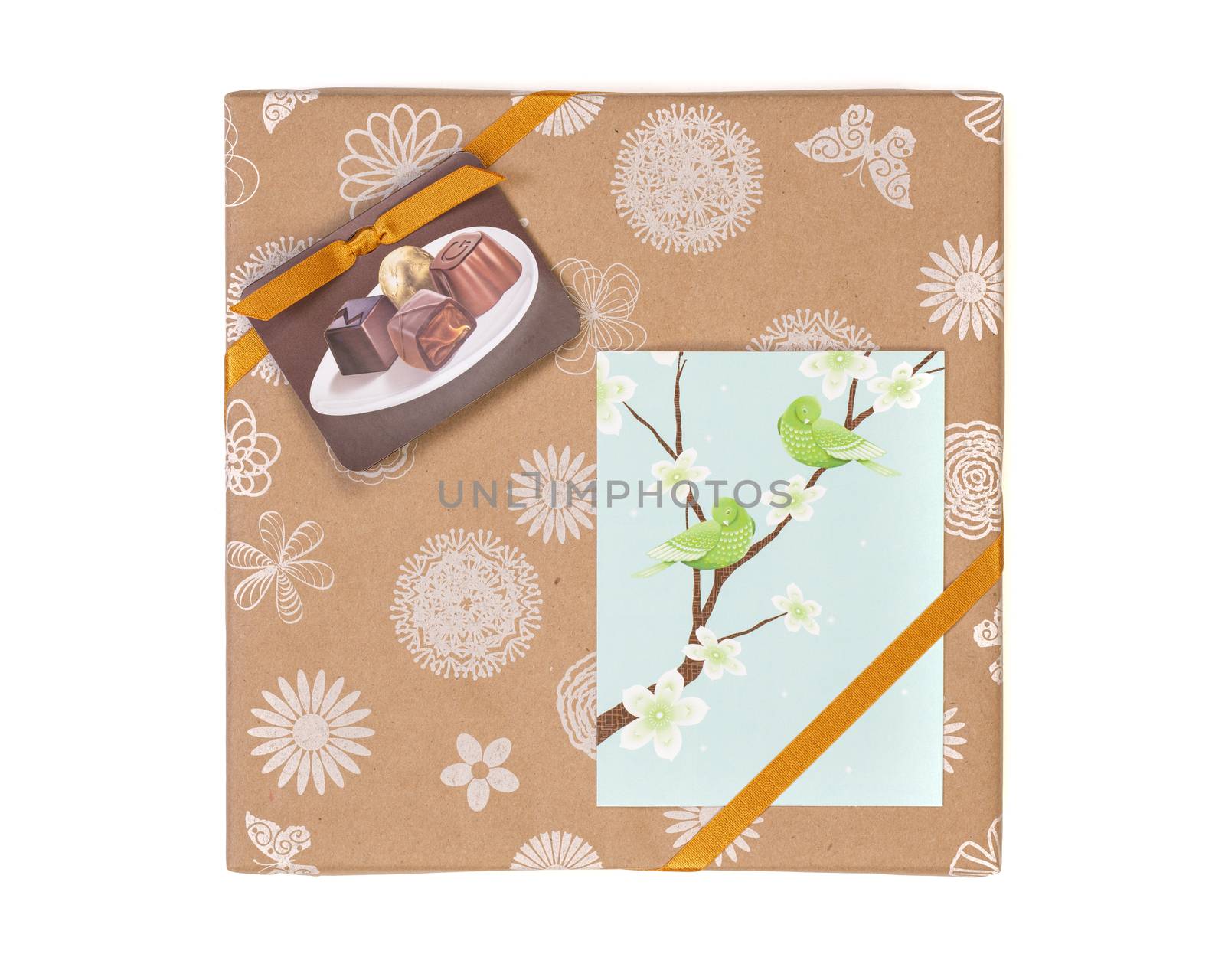 Gift wrapped box with chocolate candies and golden tape on a white background with greeting card.