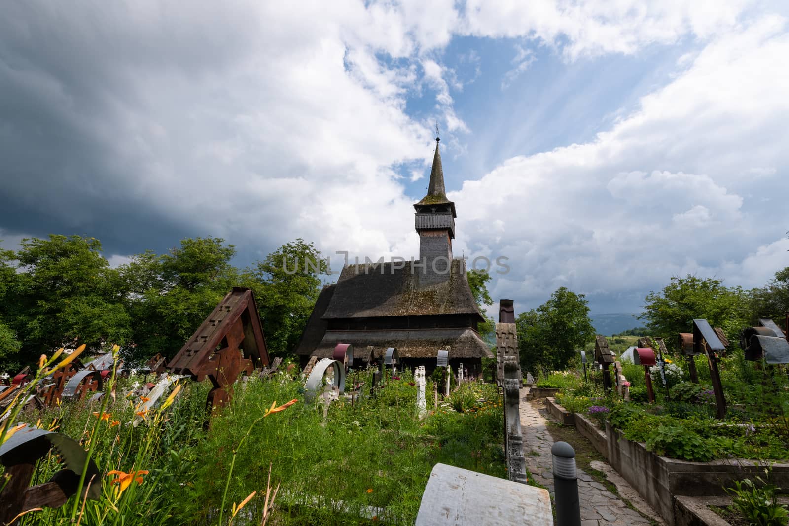 Ieud Hill Church and its graveyard, the oldest wood church in Maramures, Romania under dramatic sky. The Church belongs to a collection of Wooden Churches of Maramures, UNESCO World Heritage Site.