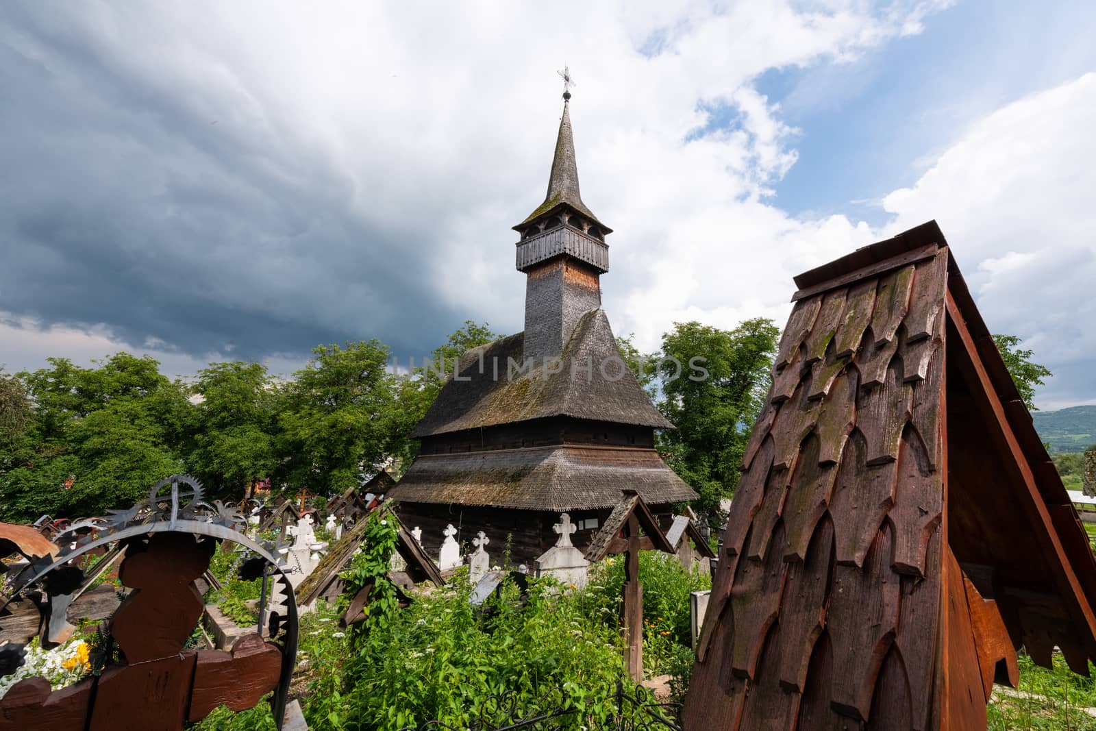 Ieud Hill Church and its graveyard, the oldest wood church in Maramures, Romania under dramatic sky. The Church belongs to a collection of Wooden Churches of Maramures, UNESCO World Heritage Site.