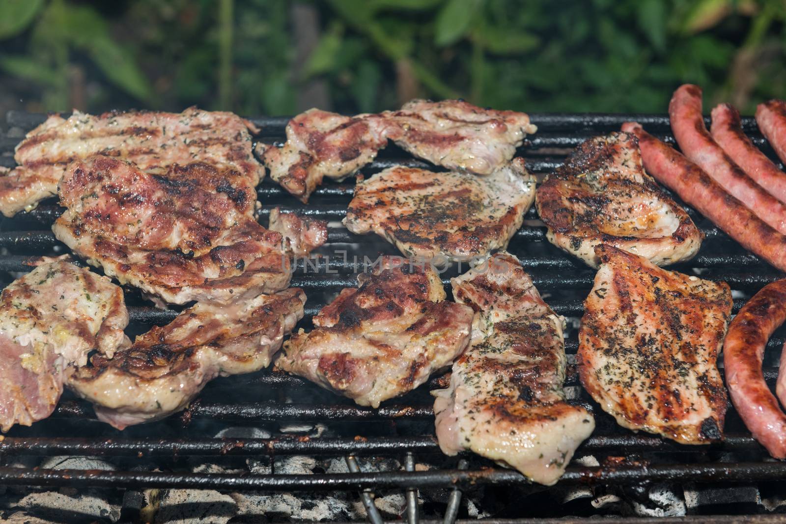 Grilling meats outdoors in a rustic old iron grill an hot coals for family gathering.