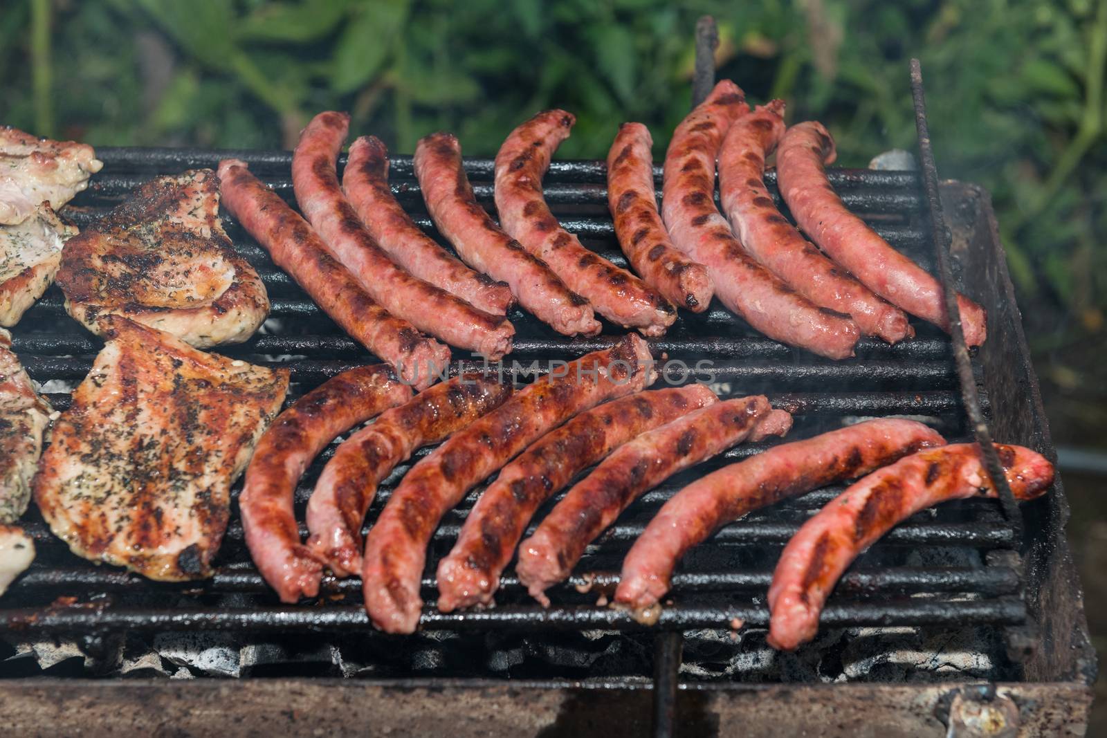 Grilling meats outdoors in a rustic old iron grill an hot coals for family gathering.