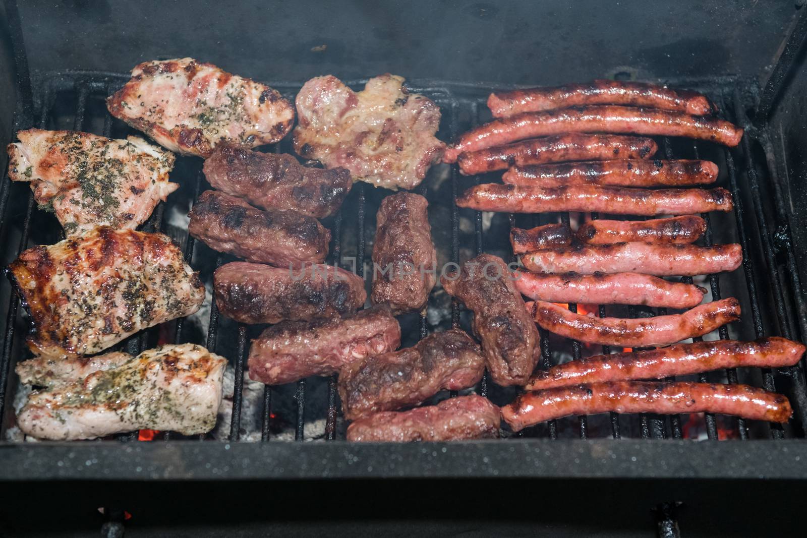 Grilling meats outdoors in a rustic old iron grill an hot coals for family gathering.