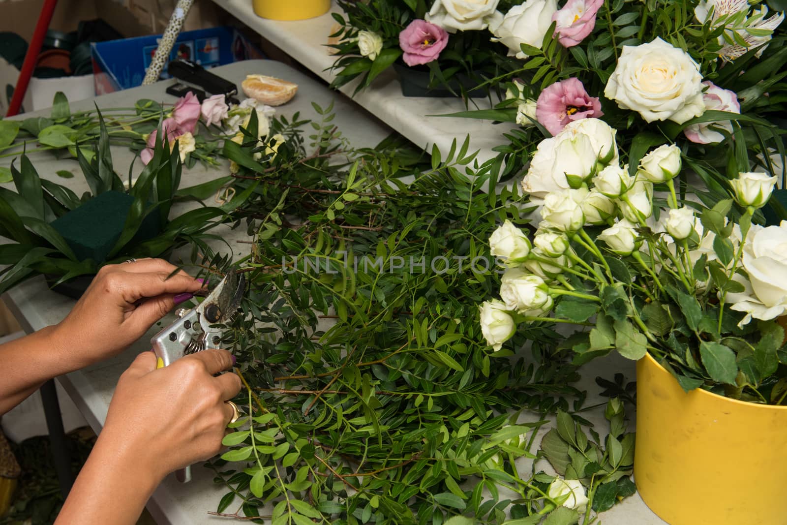 Florist female making a bouquet of different flowers at working table.