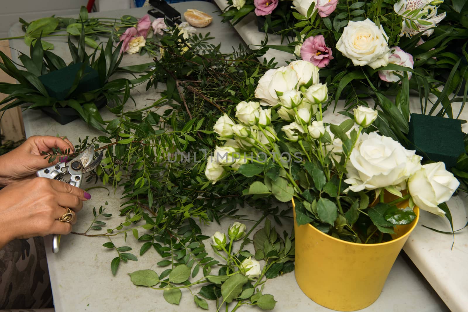 Florist female making a bouquet of different flowers at working table.