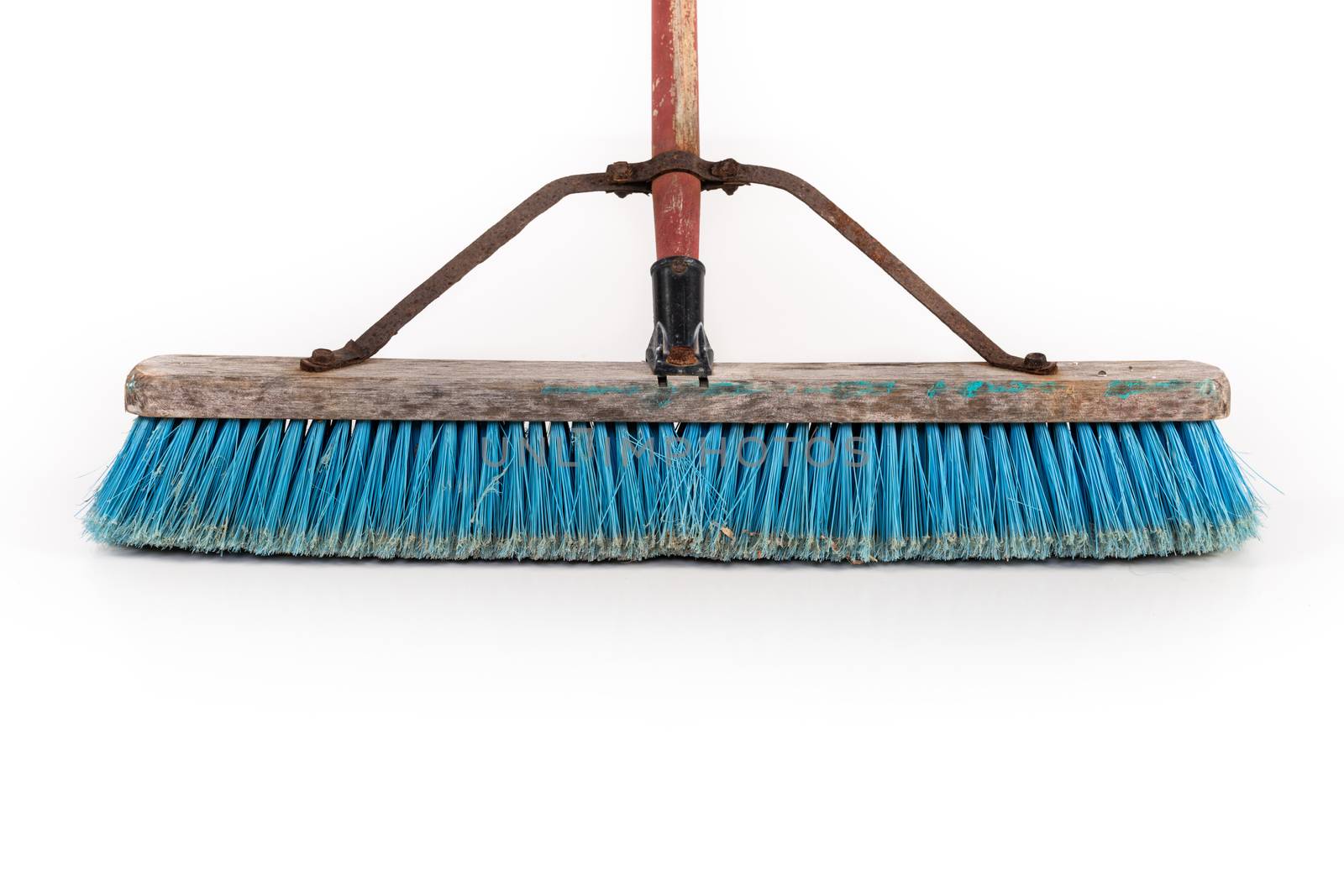 Dirty polypropylene push broom resting on a wall isolated on white.