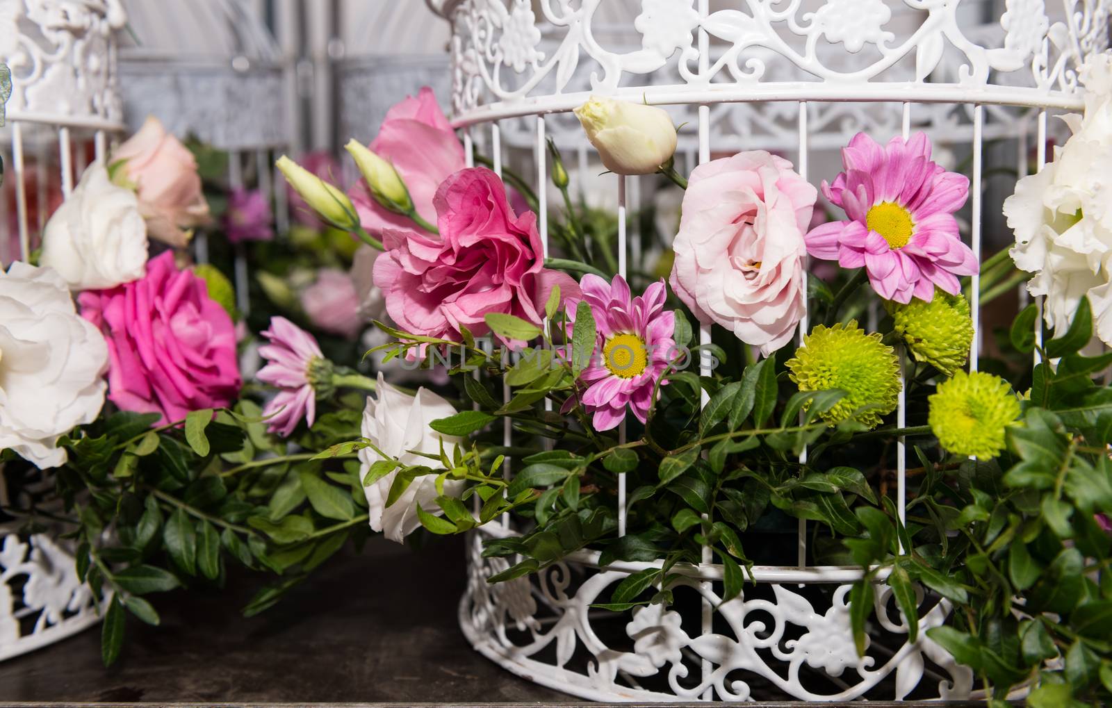 Various bridal flower heads in vintage ornate bird cage as bloom decoration at a wedding reception.