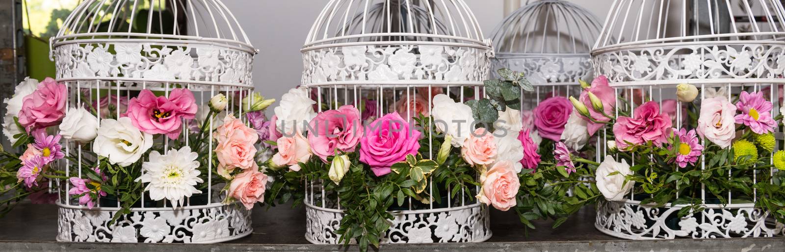 Various bridal flower heads in vintage ornate bird cage as bloom decoration at a wedding reception.