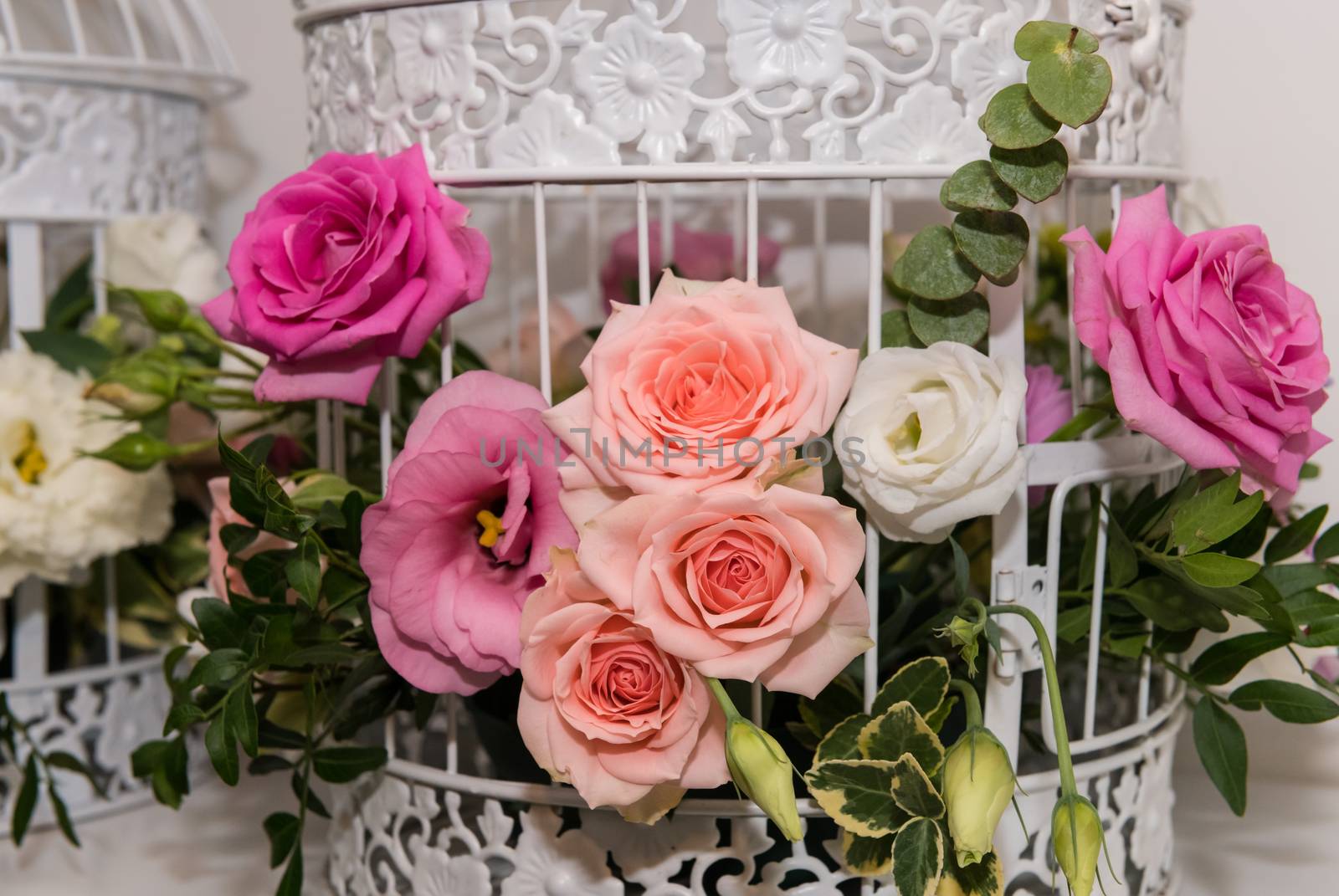 Various bridal flower heads in vintage ornate bird cage as bloom decoration at a wedding reception.