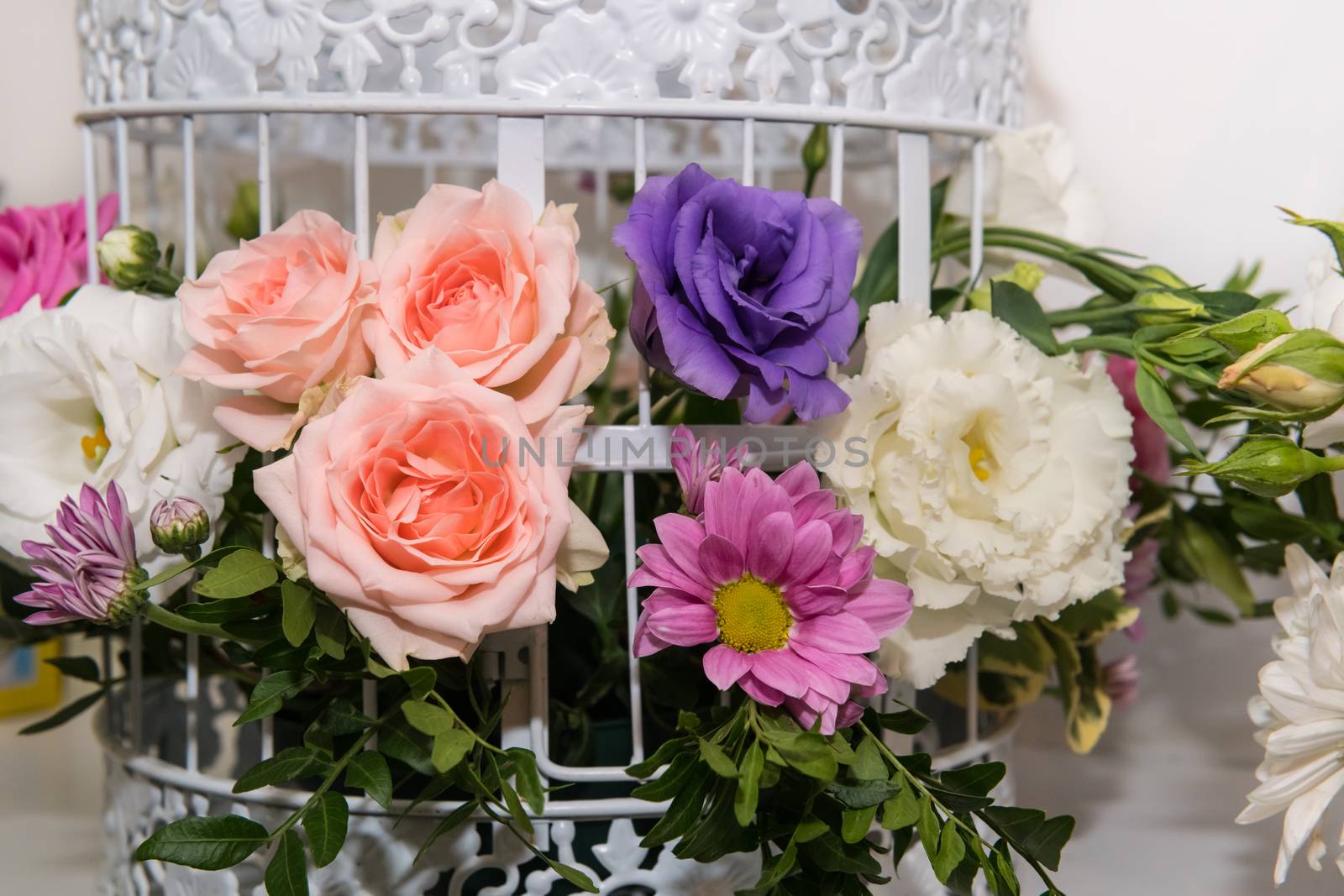 Various bridal flower heads in vintage ornate bird cage as bloom decoration at a wedding reception.