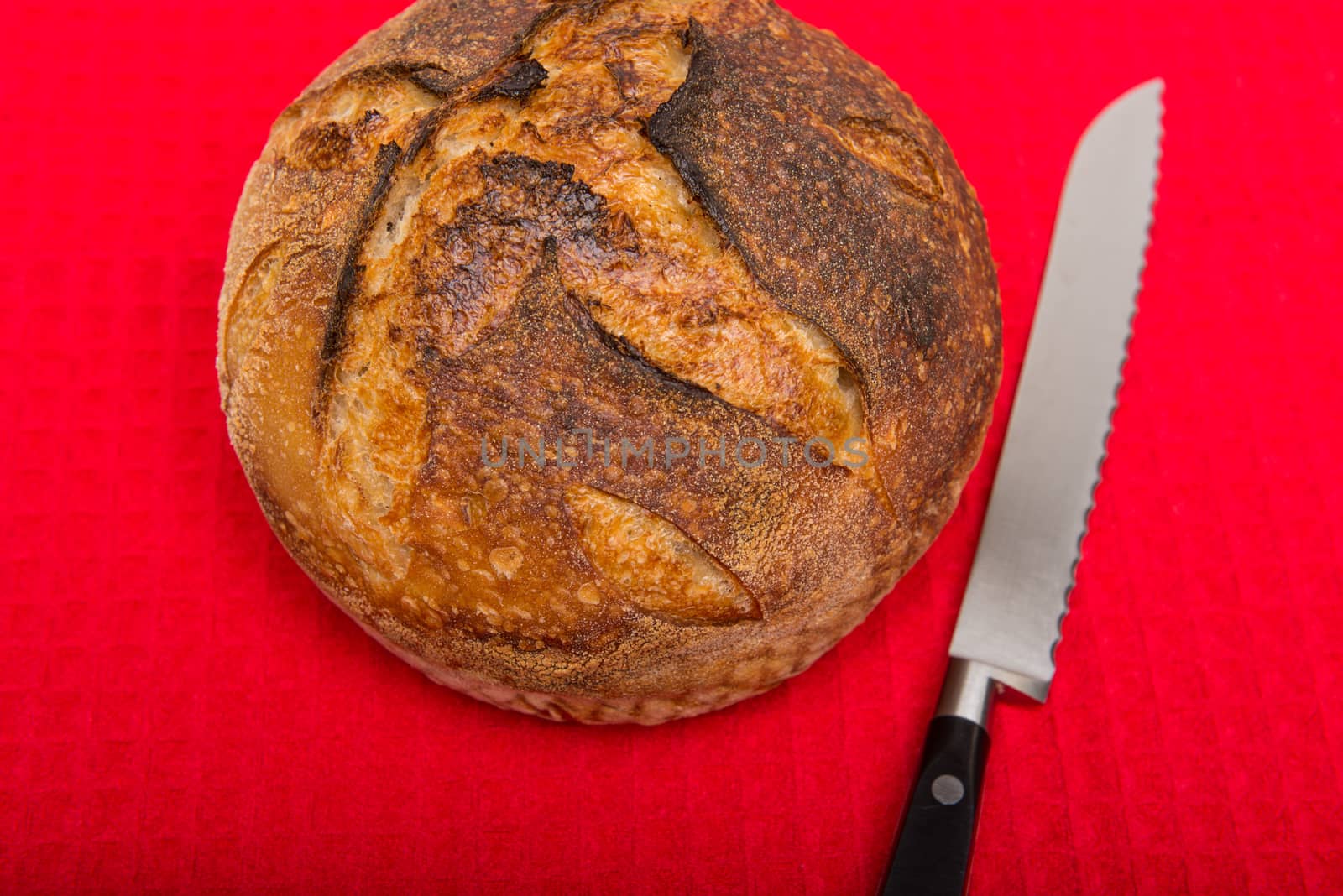 A fresh loaf of round artisan sourdough bread with a breaqd knife.