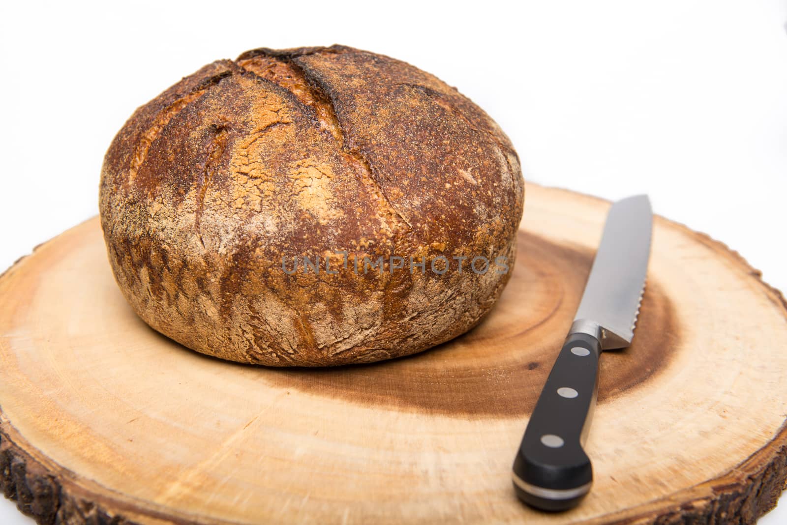 A fresh loaf of round artisan sourdough bread with a breaqd knife.