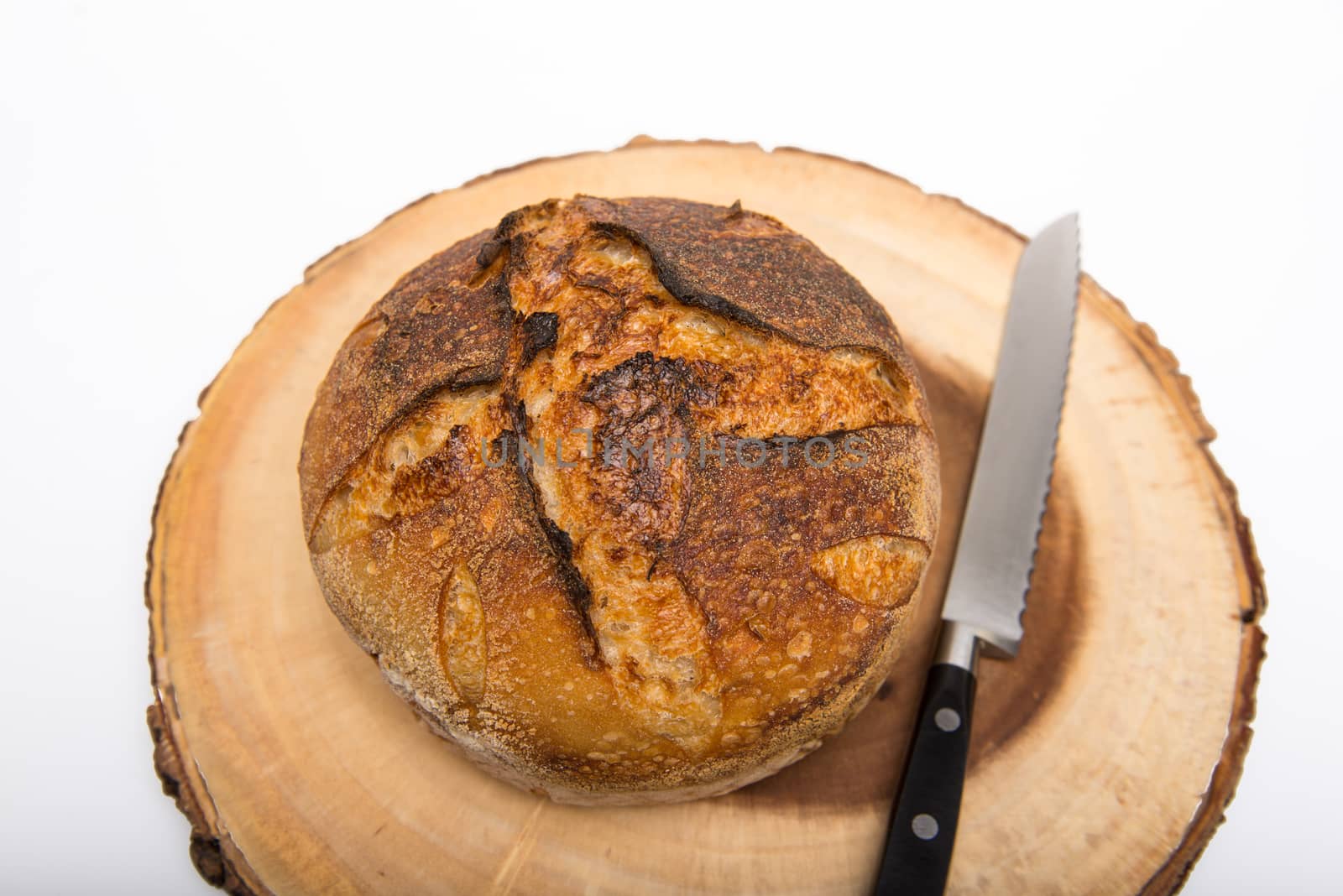 A fresh loaf of round artisan sourdough bread with a breaqd knife.
