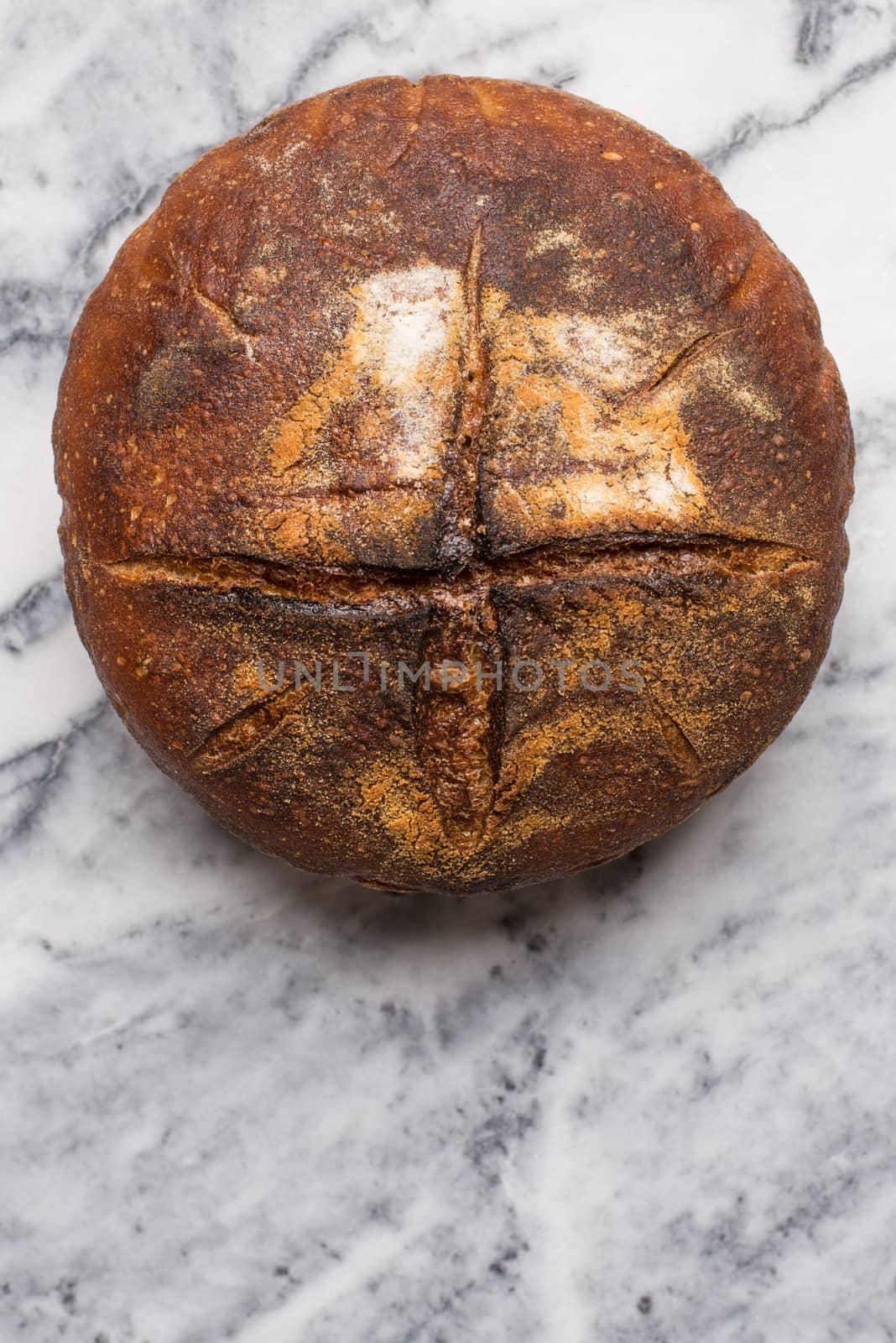 Homemade sourdough bread made in traditional style during Easter or other Christian Holidays with a simple cross signifying that bread is the body of Christ with copy space.