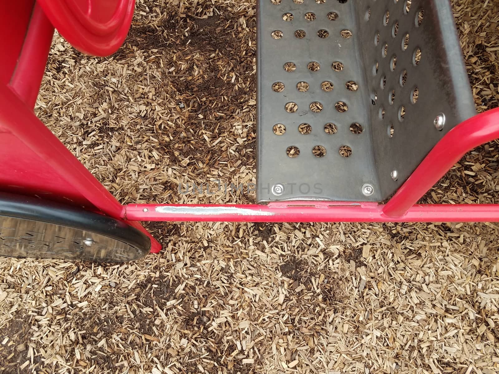 worn red metal play structure and brown mulch on playground