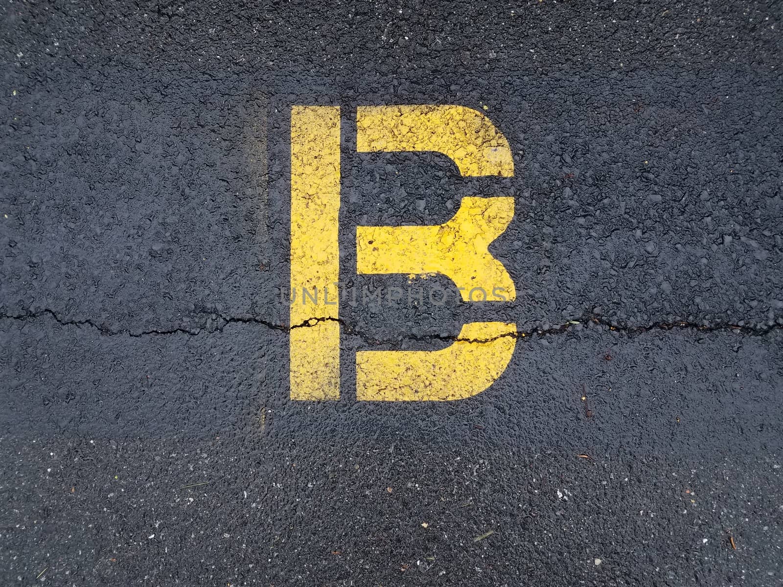 cracked black asphalt with yellow letter B by stockphotofan1