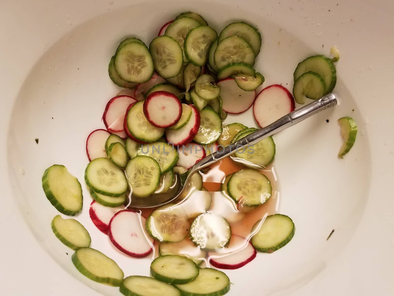 green cucumber and red radish with spoon in white container by stockphotofan1