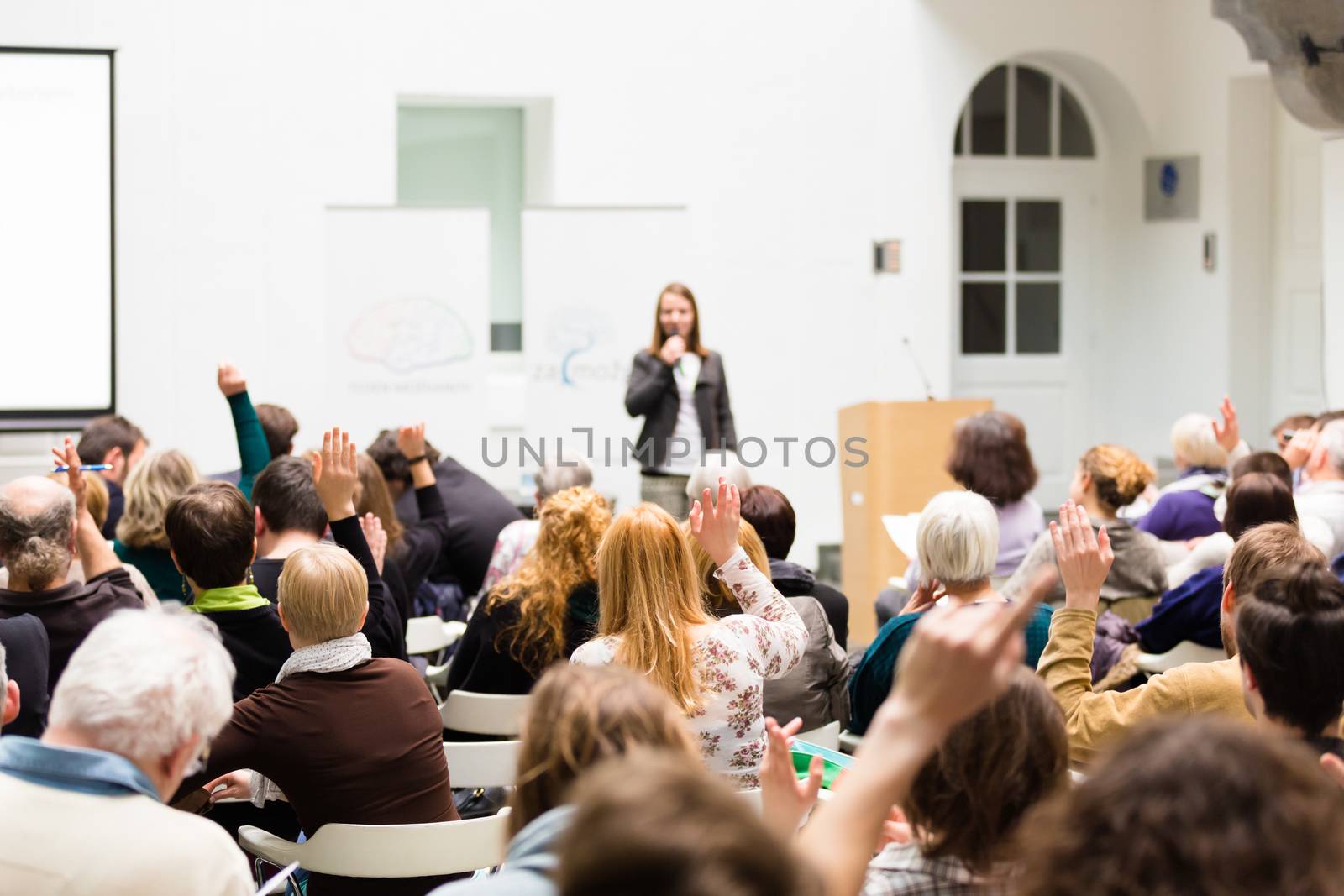 I have a question. Group of people sitting at the chairs in conference hall, raising their hands. Workshop at university. Business and Entrepreneurship event.