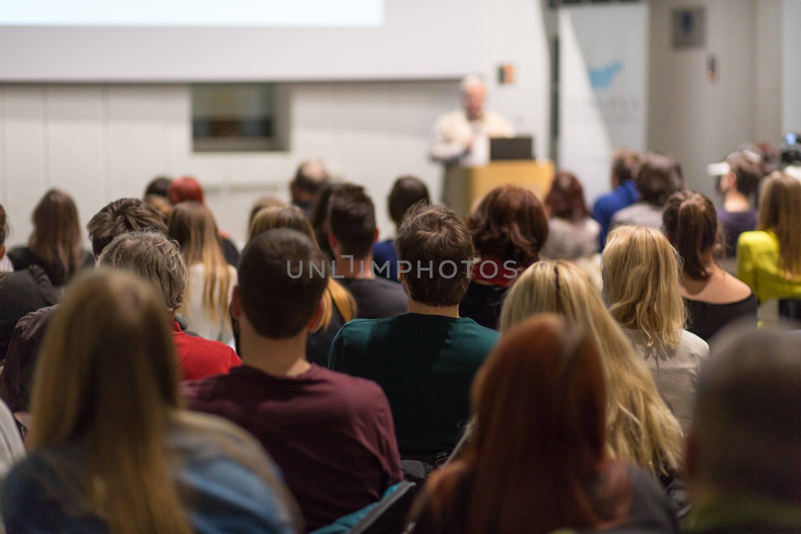 Man giving presentation in lecture hall at university. by kasto