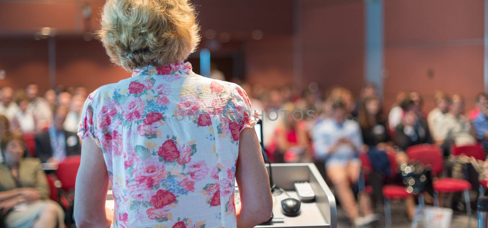 Female academic professor lecturing at Conference. Audience at the lecture hall.