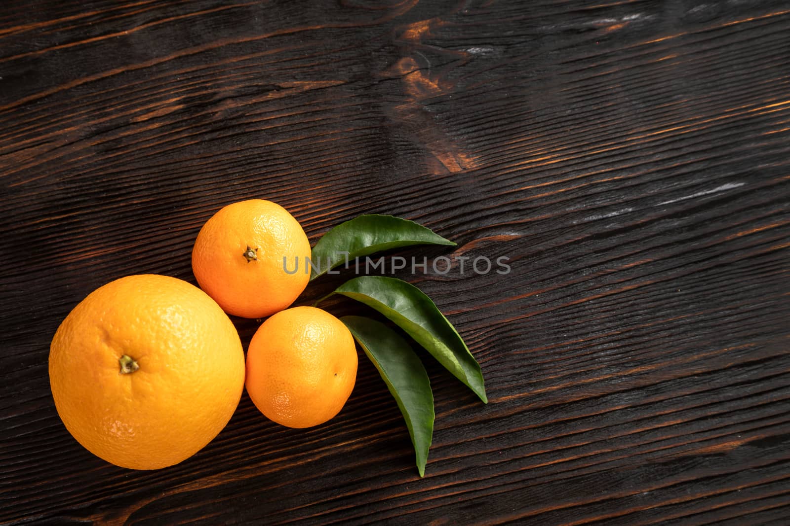 top view of whole ripe tangerines scattered on wooden chopping board