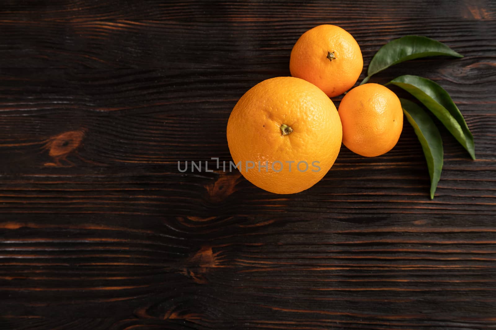 top view of whole ripe tangerines scattered on wooden chopping board