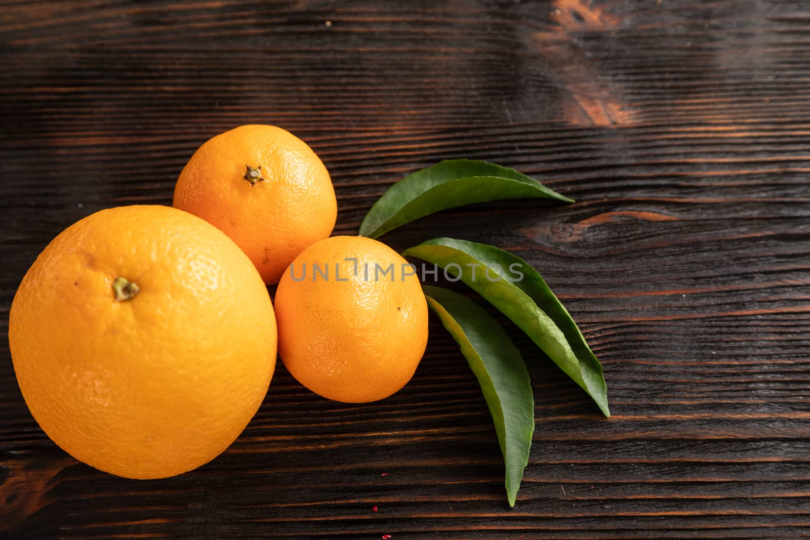 top view of whole ripe tangerines scattered on wooden chopping board