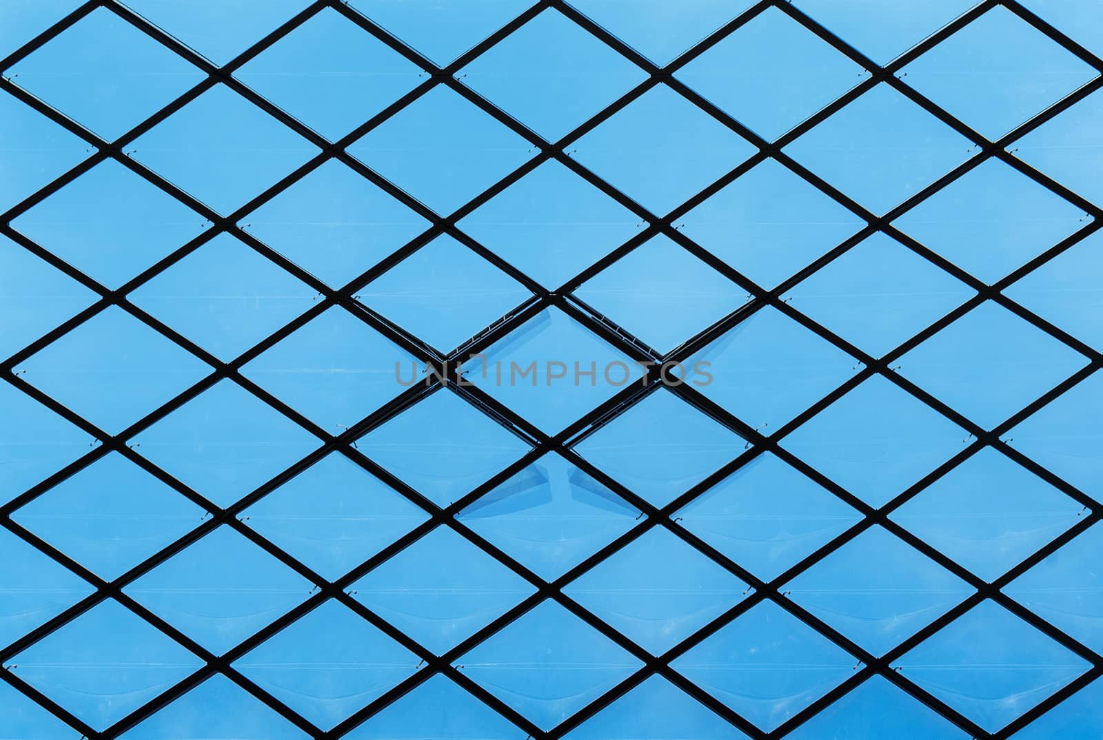 Detail of an inner ceiling with transparent windows against a clear blue sky.