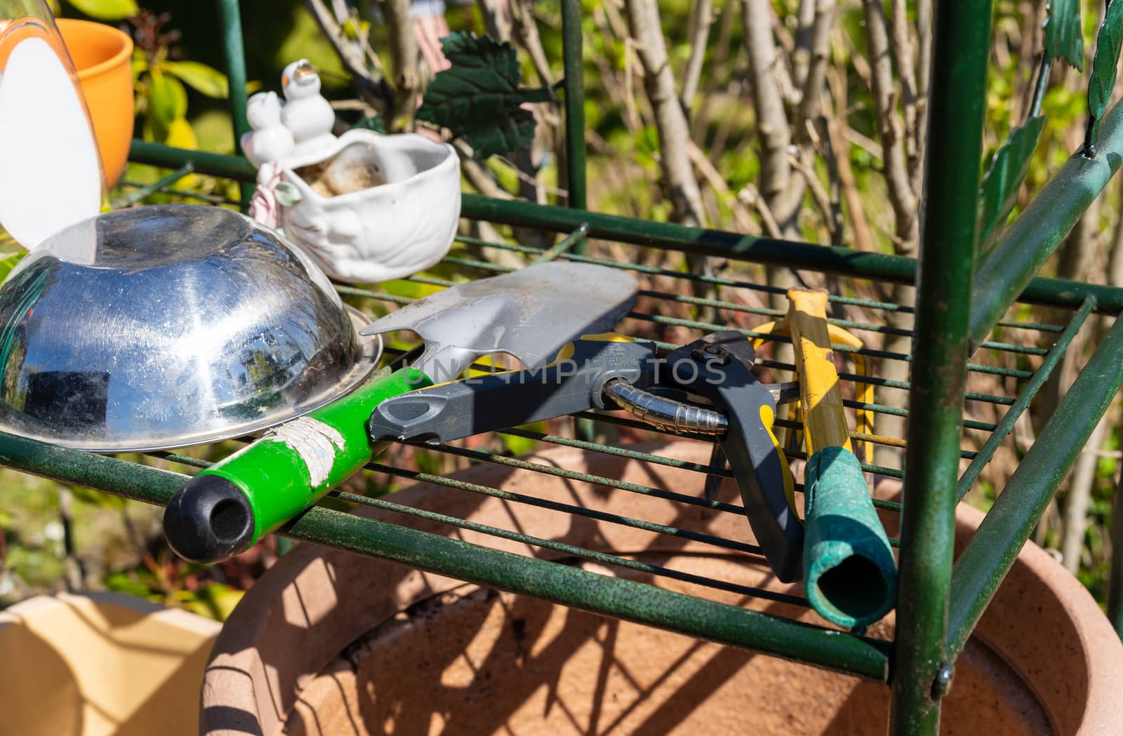 Gardening tools sitting on an outdoor shelf in a garden waiting to be used to cultivate plants.