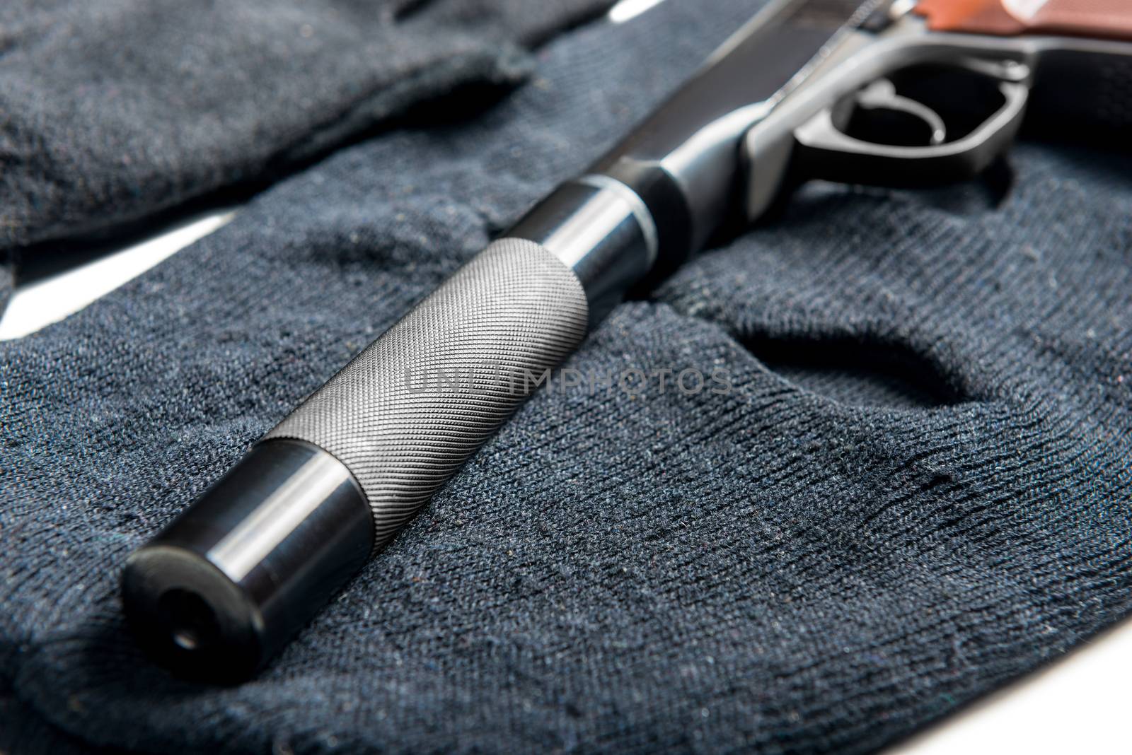 close up pistol silencer on black balaclava concept crime