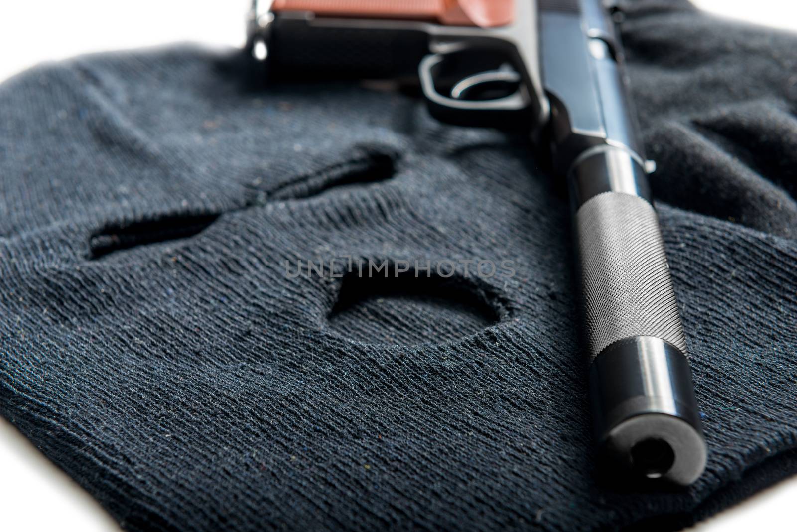 black mask balaclava and gun close up on a white table