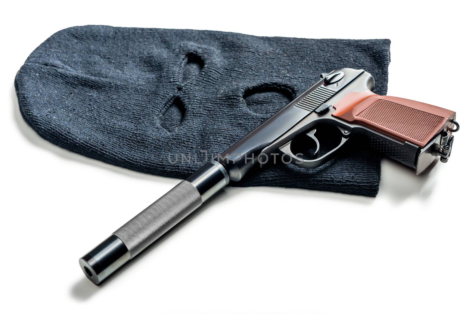 black balaclava and a pistol with a silencer close up on a white table