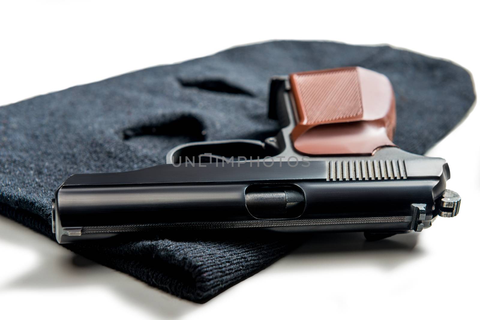 gun on black balaclava close up on white table by kosmsos111