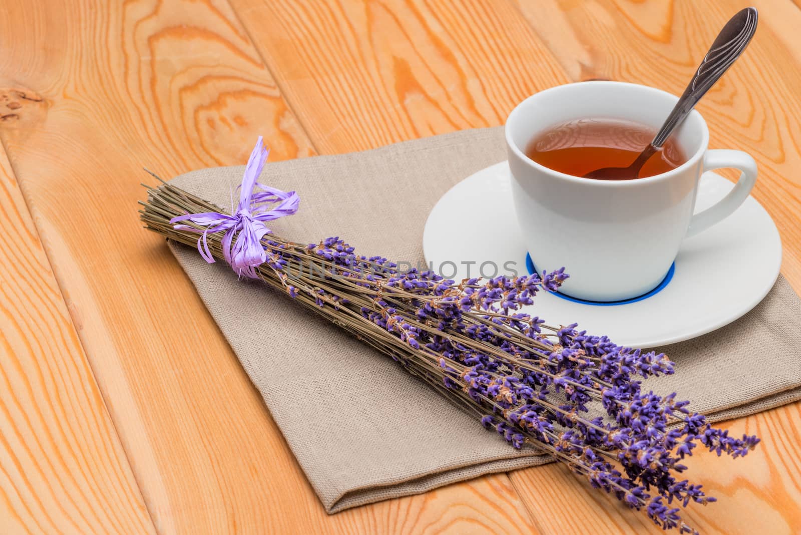 hot tea in a cup with lavender on a linen napkin close-up by kosmsos111